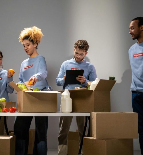 A diverse group of volunteers organizing and packing food donations at an indoor facility.
