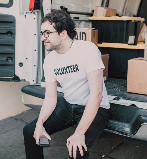 A volunteer sitting in a van organizing medicine boxes for shipment.